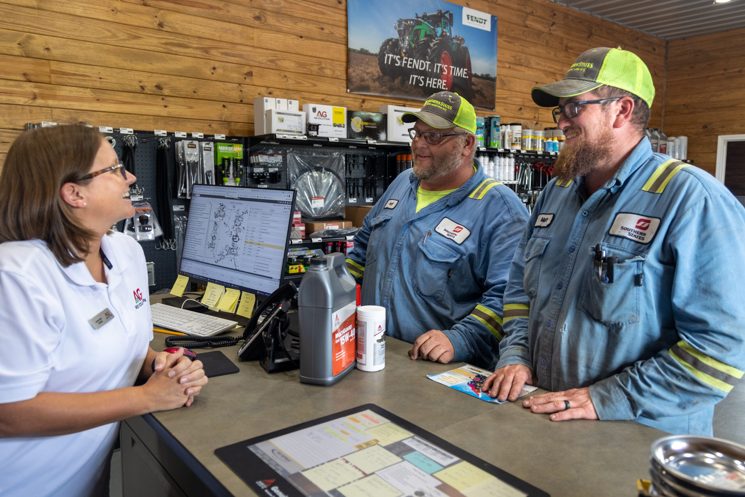 Dealership staff assists technicians at parts counter.