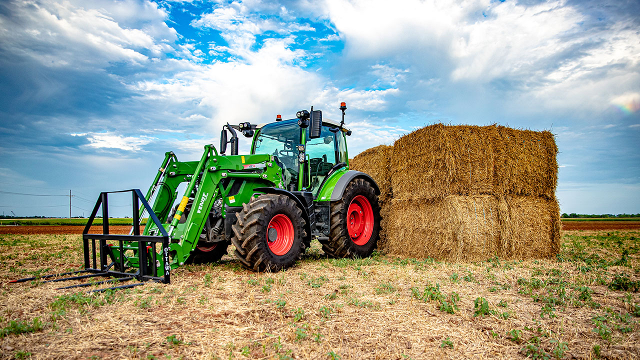 Thumbnail for Fendt 300 Vario tractor with Fendt front loader stacking hay bales in a field, showcasing AGCO precision and power.