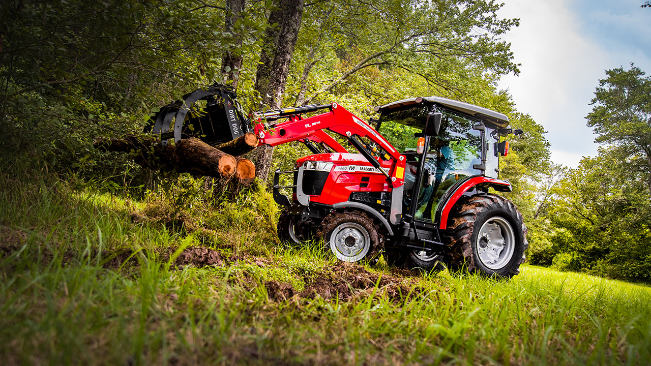 Massey Ferguson 2800M tractor hauling logs in wooded terrain, ideal for land clearing tasks.