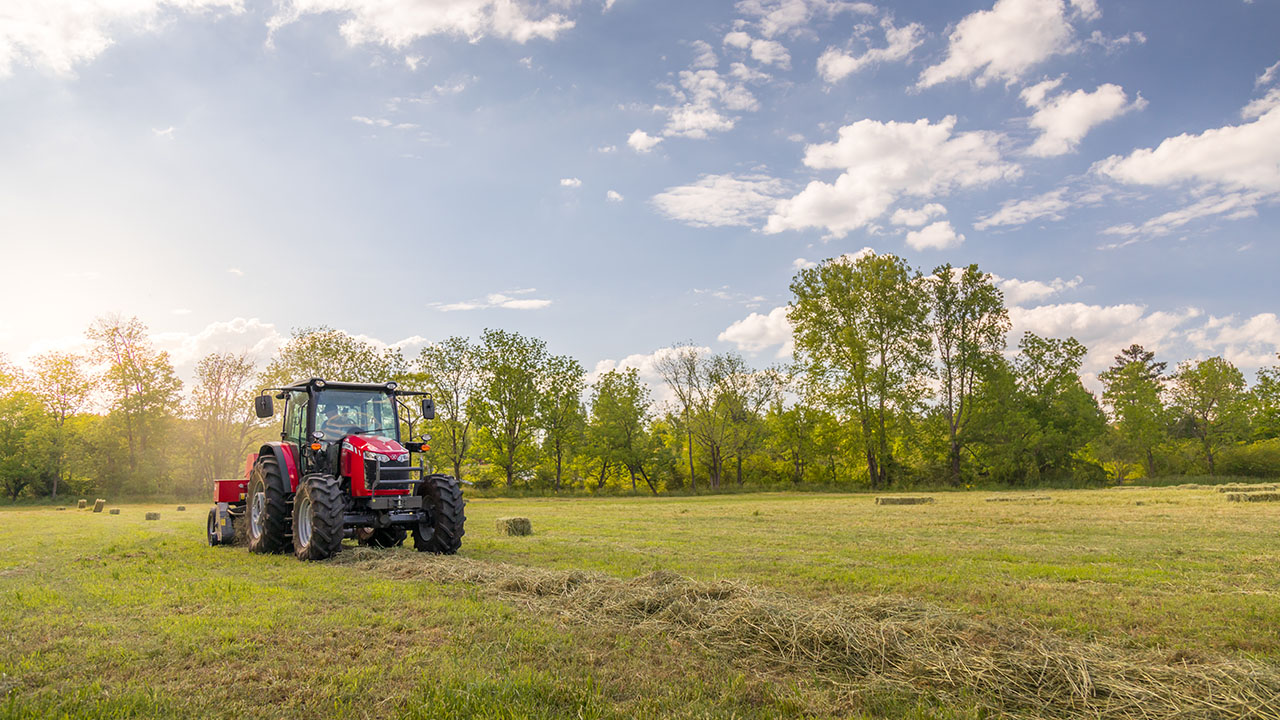 Massey Ferguson 5700 Series tractor with square baler working in hayfield under sunny sky, ideal for hay and forage operations.