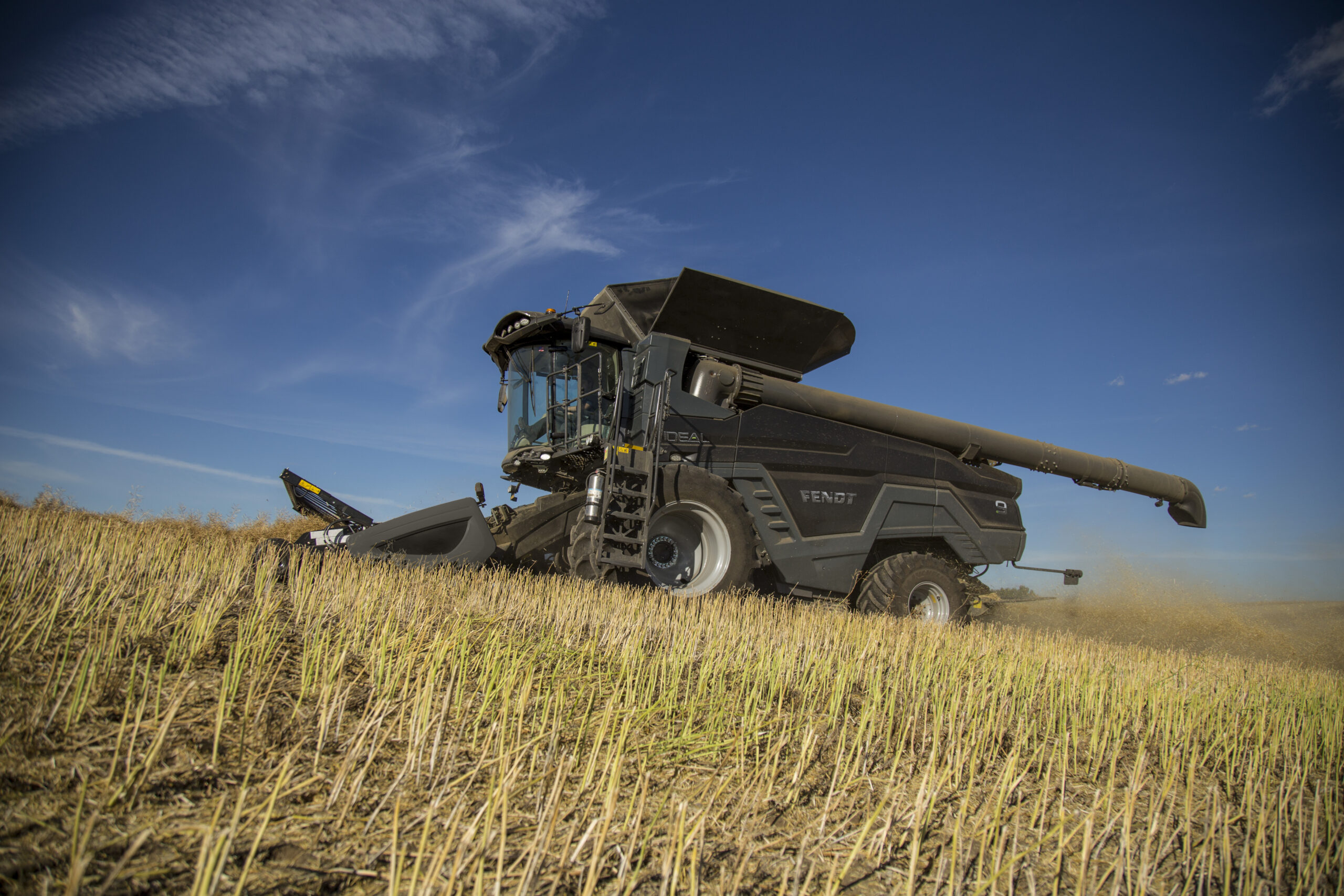 Fendt IDEAL combine harvesting canola on a hillside field, with high-capacity unload auger and precision technology visible.