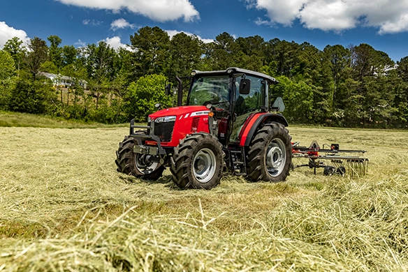 Massey Ferguson 5700 Global Series tractor raking hay with MF Rk451 rotary rake in a sunny field.