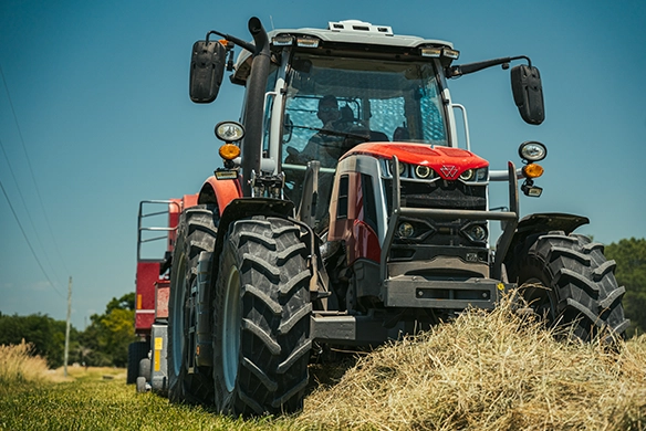 Massey Ferguson 6S Series high-horsepower tractor collecting hay in the field with a front view perspective.
