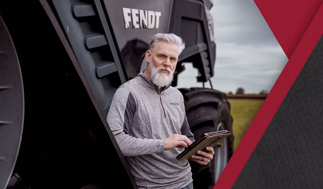 Man using tablet beside Fendt equipment, representing AGCO Finance solutions for precision farming and equipment management.