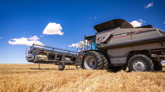 Gleaner T Series combine harvester in a wheat field with header on trailer, built for high-capacity harvesting performance.