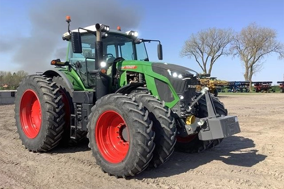 Used Fendt Vario tractor with front weight parked on gravel lot near dealership, showcasing premium ag equipment.