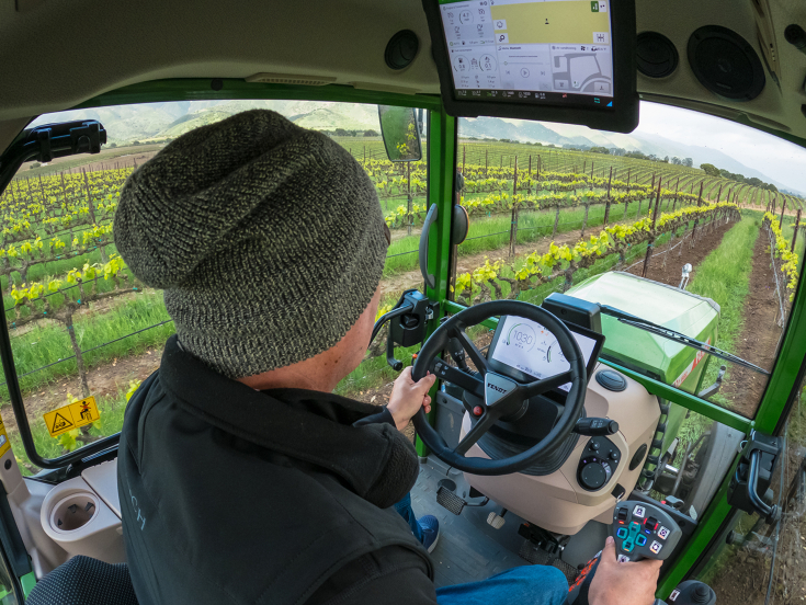 Operator driving a Fendt 200 V/F/P Vario tractor with smart tech in vineyard, showcasing in-cab controls and precision farming.