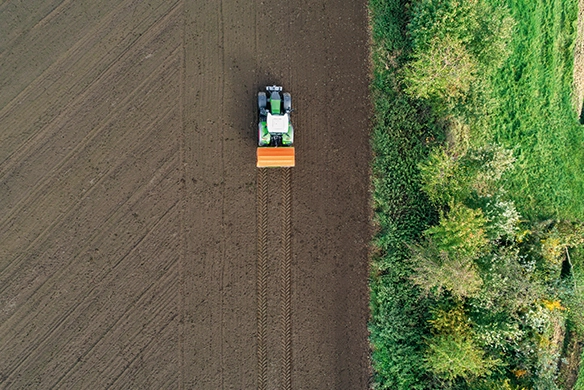 Aerial view of an Amazone ZA-TS spreader delivering even fertilizer coverage across a freshly tilled field.
