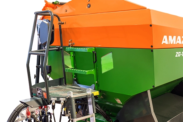 Close-up of Amazone ZG-TS fertilizer spreader with operator platform and hydraulic controls for easy maintenance and calibration.