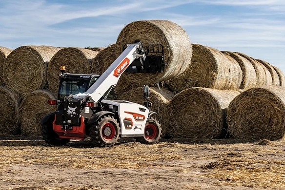 Bobcat TL519 telehandler stacking round bales with use of a bale fork.