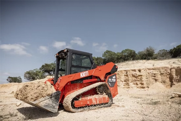 Kioti TL750 compact track loader lifting dirt at a rugged construction site