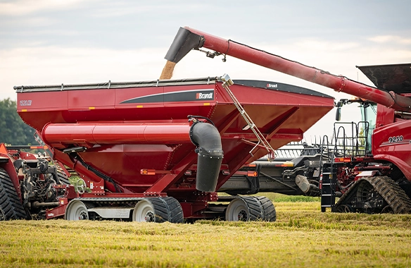 Brandt 1520XT grain cart receiving harvested grain from a combine, featuring high-capacity design and efficient unloading system in a field setting.