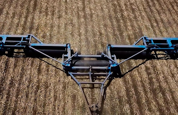 Aerial view of a Brandt land roller in operation, flattening crop residue and preparing the field for planting with wide, even coverage.