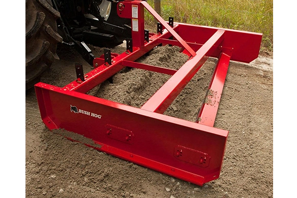 Bush Hog HDRG Series heavy-duty road grader attached to a tractor, leveling and redistributing gravel and soil for driveway and road maintenance.