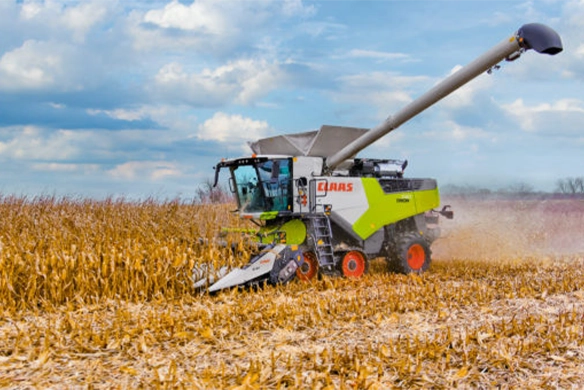 CLAAS TRION 740 combine harvester cutting through corn with extended auger and high-clearance tires, built for precision in-row harvesting.