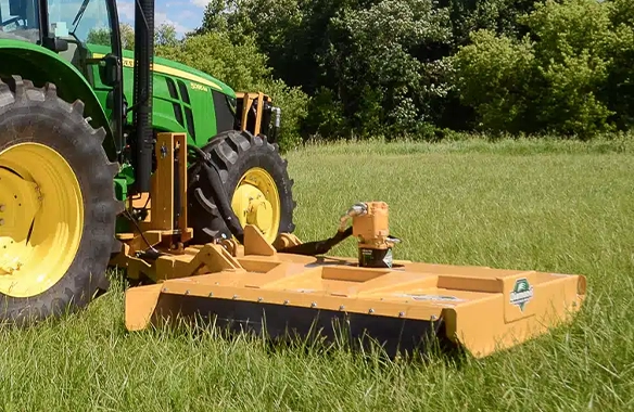 Diamond Mowers heavy-duty rotary mower attached to a tractor, cutting through tall grass in a pasture setting.