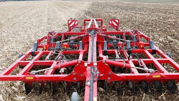 Rear view of HORSCH Tiger MT tillage tool working through corn stubble, showing multiple rows of discs and hydraulic control systems in action.