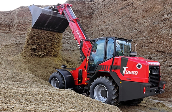 Schäffer 9660 T telescopic wheel loader operating deep inside a silage bunker, lifting with a full bucket load.