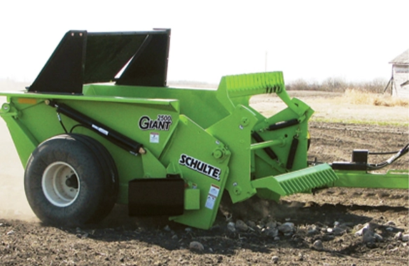 Schulte 2500 Giant rock picker in action, collecting large stones from the soil to prepare the field for planting.