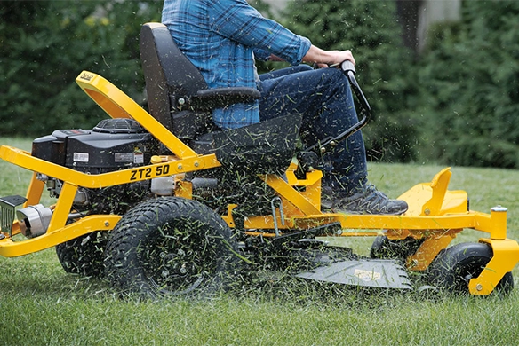 Person using a Cub Cadet ZT2 50 zero-turn mower to cut grass in a residential yard