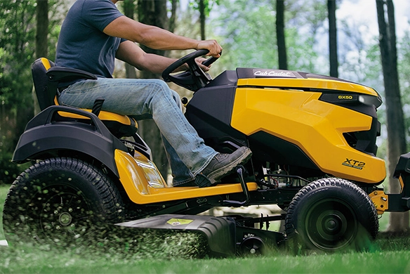 Person operating a Cub Cadet riding lawn tractor on a residential lawn