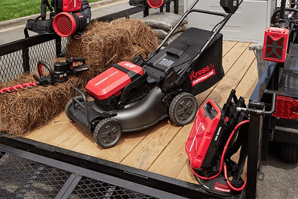 Kress commercial walk-behind mower and battery equipment loaded on a landscaping trailer