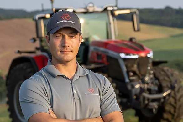 Massey Ferguson cap and polo shirt worn by operator in front of red tractor – shop discounted genuine AGCO merchandise.