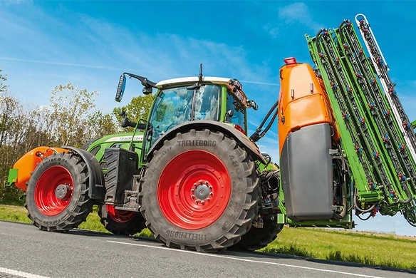 Side view of a Fendt tractor fitted with Amazone mounted sprayer and FT 1001 front tank, parked on a rural road.