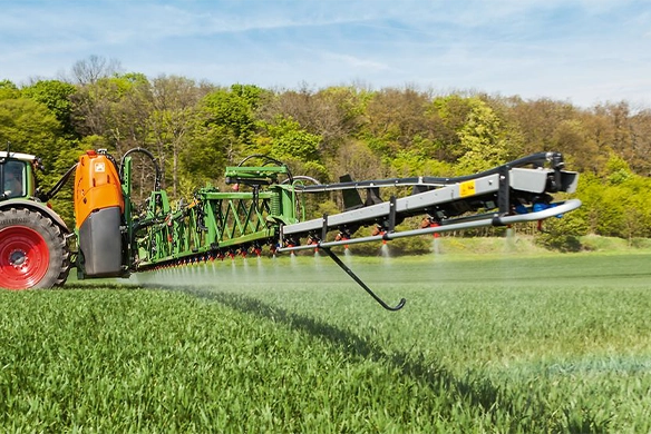 Close-up of Amazone UF02 mounted sprayer boom nozzles spraying a green field, highlighting precise application coverage.