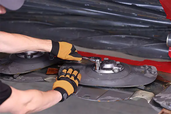 Technician adjusting hay cutter assembly – get savings on genuine AGCO hay tools and parts.