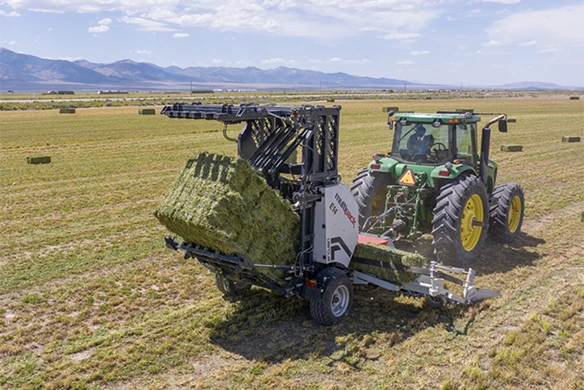 Arcusin Multipack D14 bale bundler lifting hay bales in alfalfa field behind a tractor.