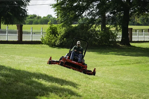Operator mowing sloped terrain with an Exmark Lazer Z zero-turn mower for professional-grade landscaping.