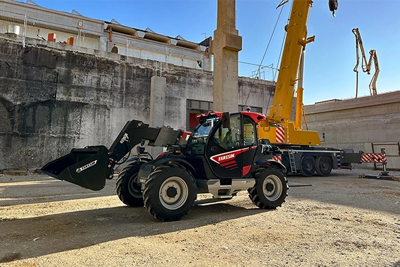 Faresin FS Middle telehandler transporting a multi-purpose attachment outside a red agricultural building.