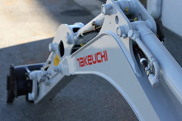 Worker operating Takeuchi TB210R compact excavator, exiting a building through a narrow doorway.