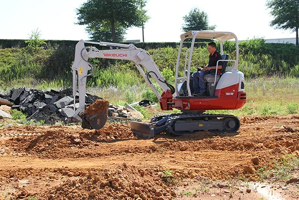 Takeuchi TB225 mini excavator working near construction debris on a dirt path.