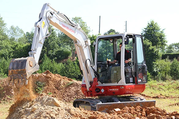 Operator using Takeuchi TB240 compact excavator to move dirt on a construction site.