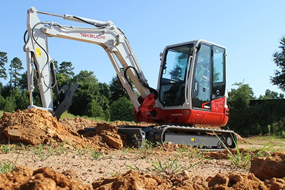 Operator using Takeuchi TB250-2 compact excavator to move dirt on a construction site.