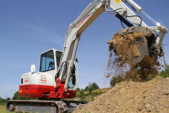 Takeuchi TB260 compact excavator dumping soil on jobsite for efficient earthmoving performance.