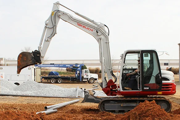 Takeuchi TB290 mini excavator with dozer blade working on commercial jobsite.