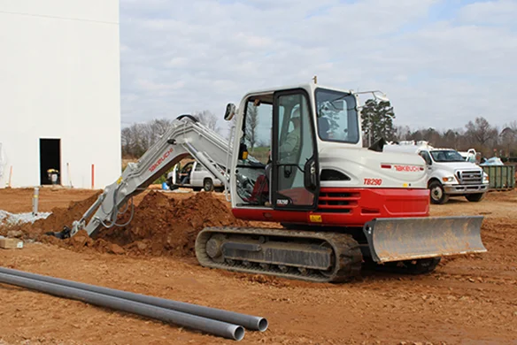 Takeuchi TB290 mini excavator with dozer blade working on commercial jobsite.