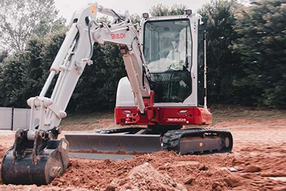 Takeuchi TB335R compact excavator digging foundation next to residential home.
