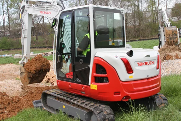 Operator using Takeuchi TB370 excavator to dig earth on a jobsite, demonstrating its digging capabilities.