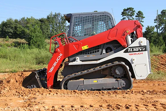 Takeuchi TL10V2 compact track loader digging into soil on a jobsite.
