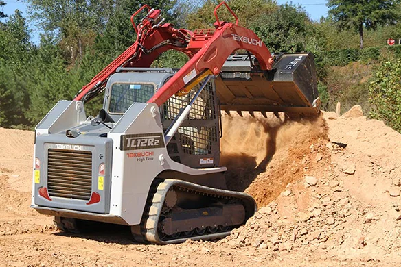 Takeuchi TL12R2 high-flow compact track loader pushing a load of sand on a slope.