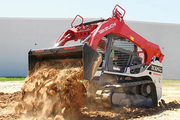 Takeuchi TL12V2 compact track loader dumping large load of dirt in active worksite.