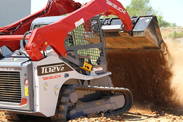 Takeuchi TL12V2 loader spreading soil, highlighting high-flow hydraulic capability.