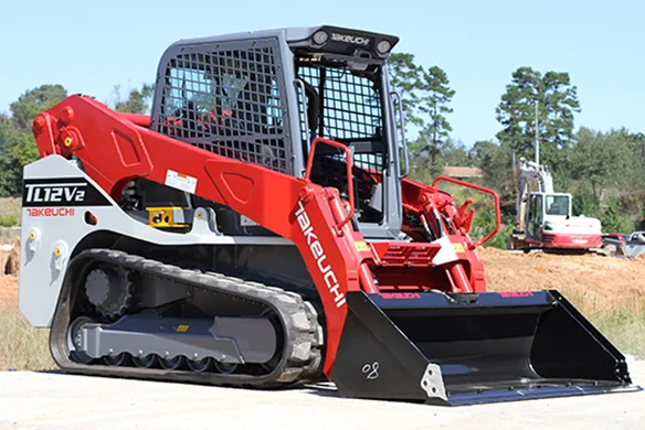 Takeuchi TL12V2 loader spreading soil, highlighting high-flow hydraulic capability.