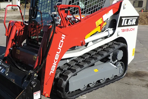 Takeuchi TL6R loader close-up showing tracks, lift arms, and robust machine frame.