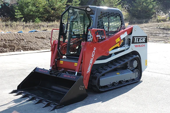 Takeuchi TL6R compact track loader with root rake bucket on pavement, ideal for site prep and land clearing.