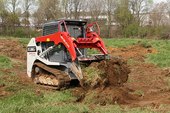 Takeuchi TLB2R2 compact track loader tearing up sod in fieldwork, designed for landscaping and ag jobs.